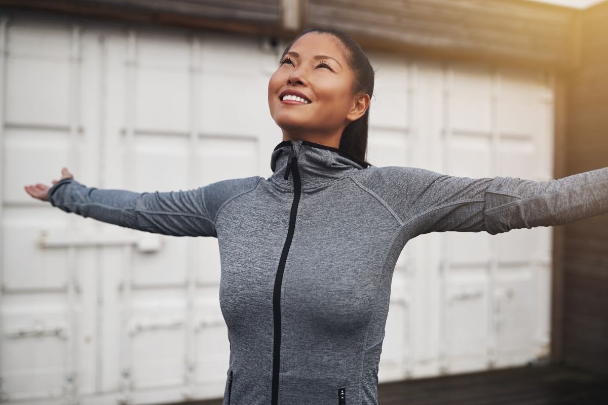 Asian Woman Out Jogging with Her Arms Raised Skyward after using menthol deodorant
