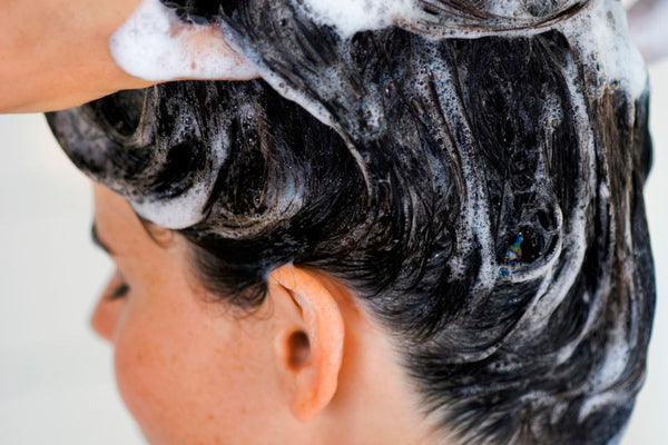 Woman washing hair with shampoo