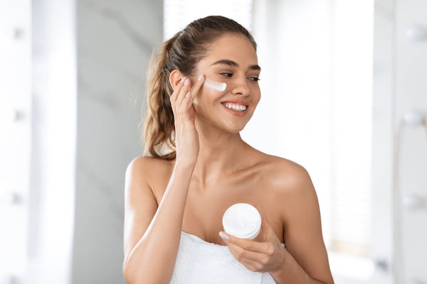 woman with sensitive skin Applying Facial Moisturizer Cream in Modern Bathroom